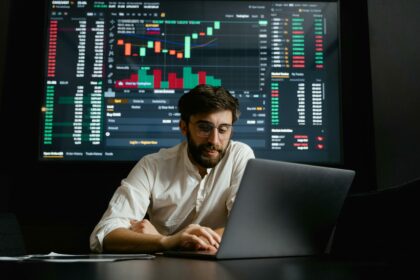 Male analyst studies cryptocurrency trends at a workstation with multiple displays showing market data.